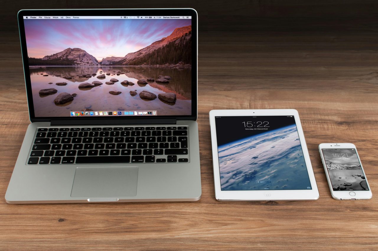 An Apple iphone, smartphone and tablet on a desk.