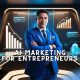 AI marketing for entrepreneurs represented by businessman in blue suit in a digital AI workspace surrounded by marketing charts, automation robots, and futuristic UI elements