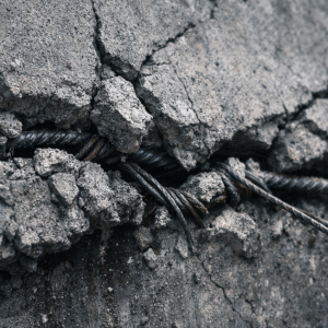 Cracked concrete under structural tension with exposed rebar, symbolizing decision hardening under pressure in AI startups.