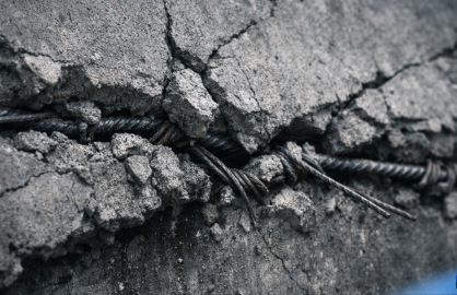 Cracked concrete under structural tension with exposed rebar, symbolizing decision hardening under pressure in AI startups.