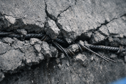 Cracked concrete under structural tension with exposed rebar, symbolizing decision hardening under pressure in AI startups.